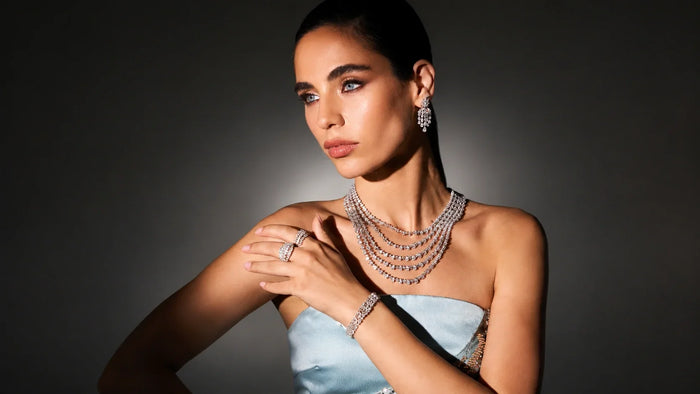  Spectrum Jewels model wearing layered diamond necklace, chandelier earrings, diamond rings, and bracelet in blue gown.