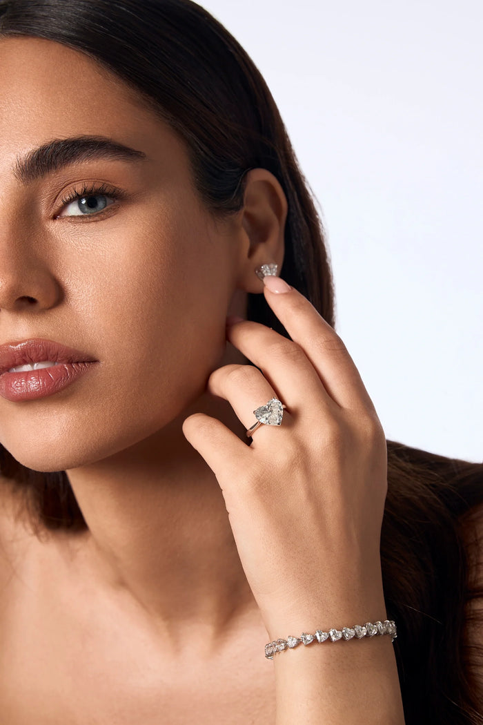Spectrum Jewels woman wearing a pear-shaped diamond engagement ring, diamond stud earrings, and a diamond tennis bracelet.