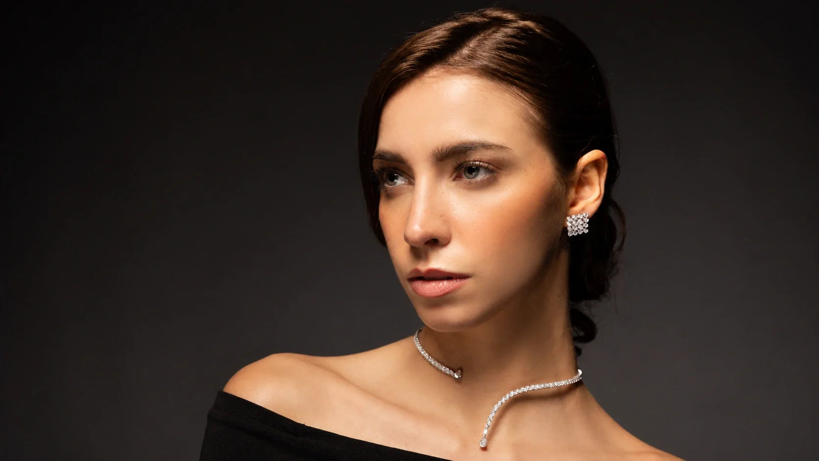 Spectrum Jewels model wearing diamond stud earrings and a delicate diamond choker necklace in an elegant black outfit.