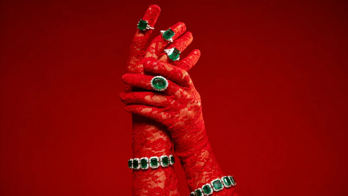 Emerald and diamond statement rings and bracelets styled over red lace gloves by Spectrum Jewels.