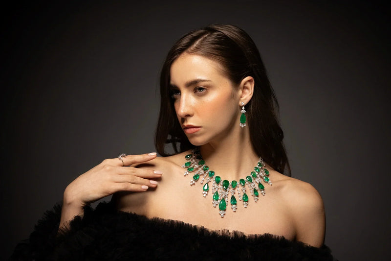Spectrum Jewels natural emerald and diamond statement necklace with matching emerald drop earrings elegantly showcased on a model.