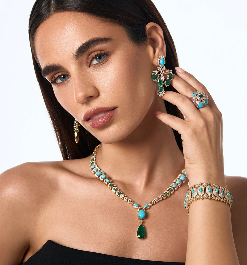 Spectrum Jewels model wearing a turquoise and emerald jewelry set with statement earrings, necklace, ring, and bracelet.